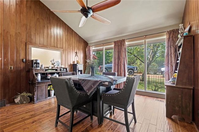 Dining room featuring wood walls, light wood-type flooring, ceiling fan, and lofted ceiling | Image 13
