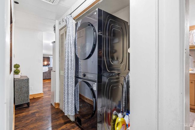 Laundry room with stacked washer / drying machine and wood finished floors | Image 15