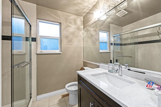 Bathroom featuring toilet, tile patterned floors, baseboards, a shower stall, and vanity | Image 26