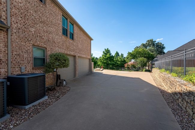 View of side of property with driveway, a garage, and brick siding | Image 6