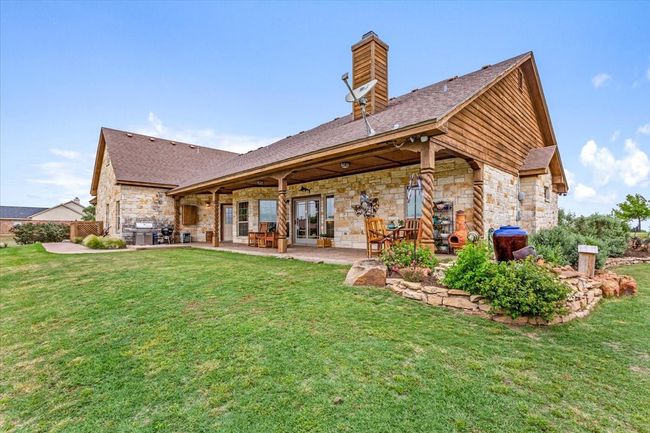 Rear view of property with stone siding, a lawn, a patio, and a chimney | Image 29