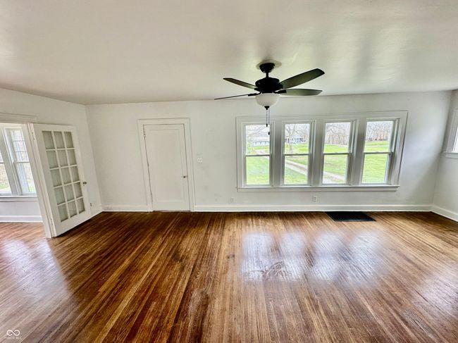 unfurnished living room with visible vents, baseboards, a ceiling fan, and dark wood-style floors | Image 18