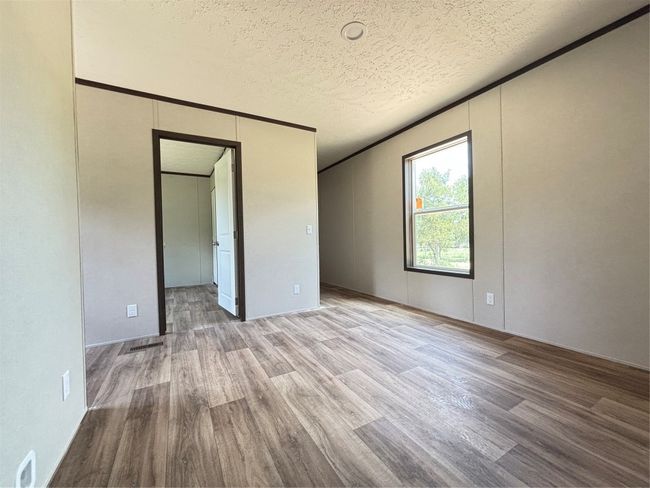 Unfurnished bedroom featuring wood look finished floors, a textured ceiling, and a walk in closet | Image 20