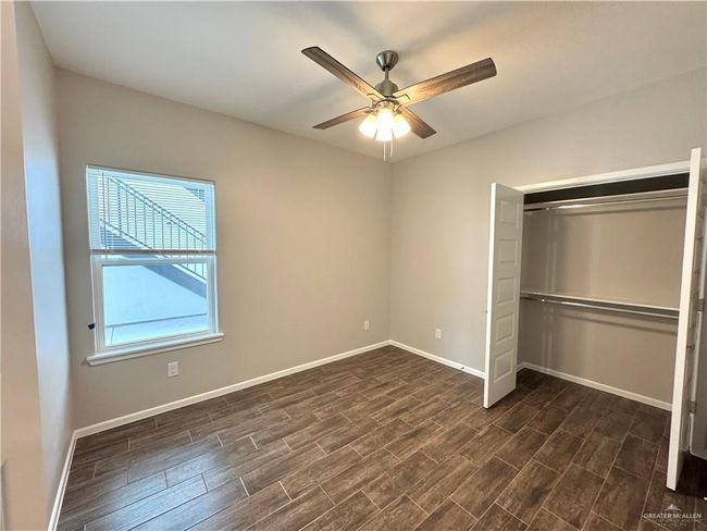Unfurnished bedroom featuring dark wood-style floors, baseboards, a closet, and ceiling fan | Image 12