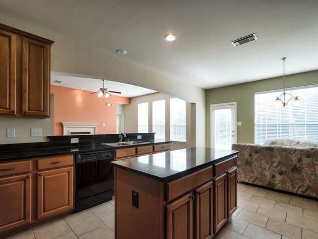 Kitchen featuring black dishwasher, open floor plan, a sink, ceiling fan, and healthy amount of natural light | Image 18