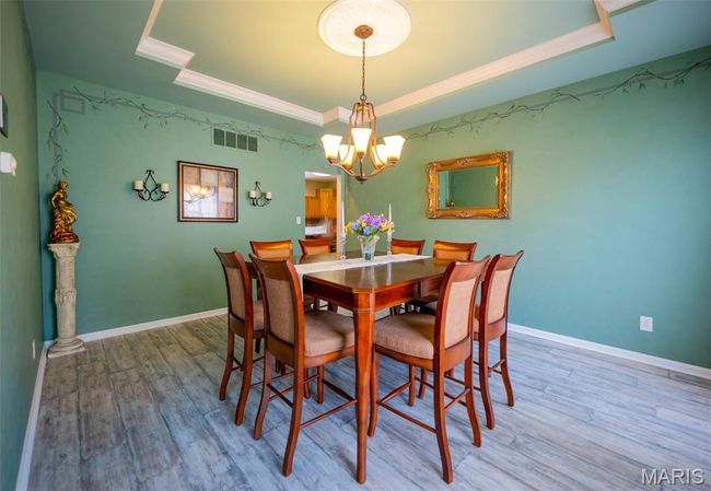 Dining area with a raised ceiling, a chandelier, wood finished floors, and crown molding | Image 7