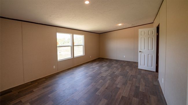 Unfurnished room featuring a textured ceiling, crown molding, a decorative wall, dark wood-type flooring, and recessed lighting | Image 13