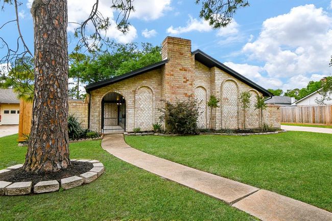 This charming brick home features a sloped roof and a welcoming arched entryway. The well-maintained front yard is landscaped with trees and shrubs, offering great curb appeal. | Image 8