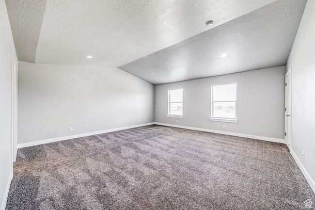 Primary bedroom featuring lofted ceiling, a textured ceiling, baseboards, and carpet flooring | Image 11
