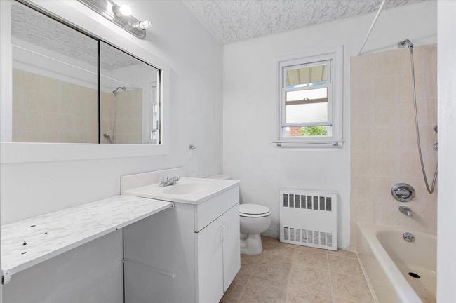 Bathroom with radiator, vanity, toilet, tub / shower combination, and tile patterned floors | Image 8