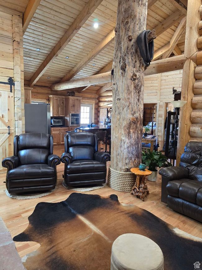 Living room featuring a barn door, beamed ceiling, and wood finished floors | Image 69