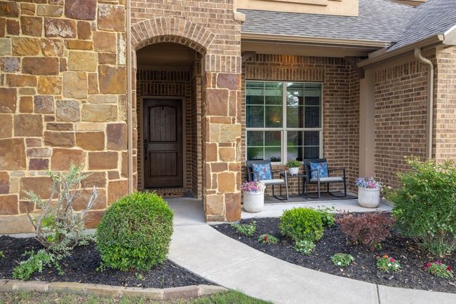 View of exterior entry featuring a porch, brick siding, and a shingled roof | Image 15