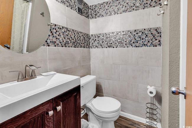 Bathroom featuring toilet, vanity, tile walls, and wood finished floors | Image 10