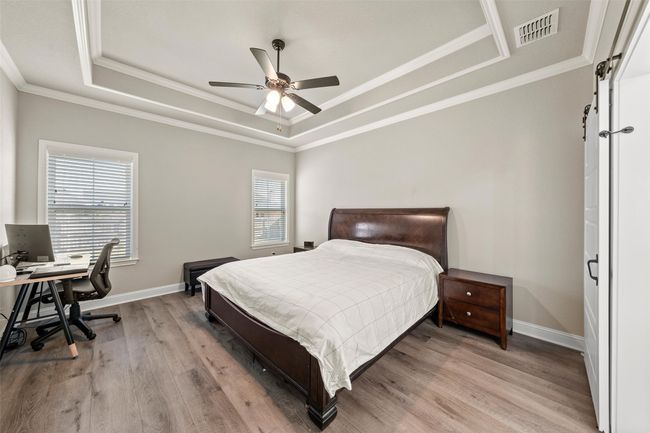 Bedroom with a raised ceiling, light wood-type flooring, baseboards, and visible vents | Image 11