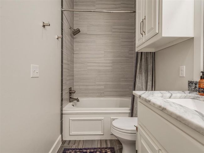 Full bathroom featuring toilet, washtub / shower combination, vanity, wood finished floors, and baseboards | Image 21