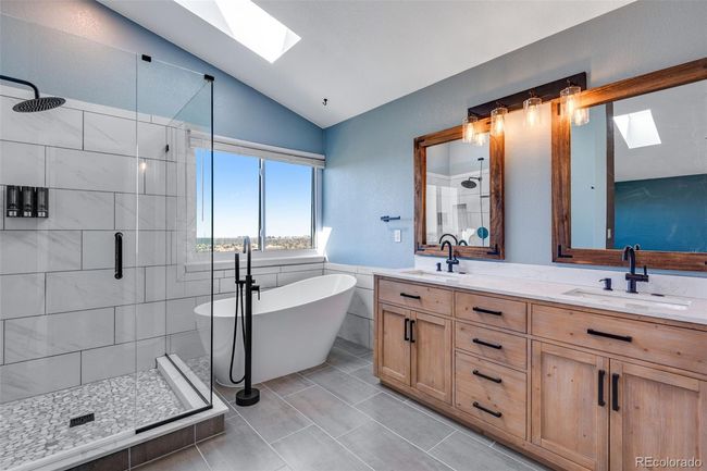 Full bathroom featuring a sink, a shower stall, a freestanding tub, and lofted ceiling with skylight | Image 18