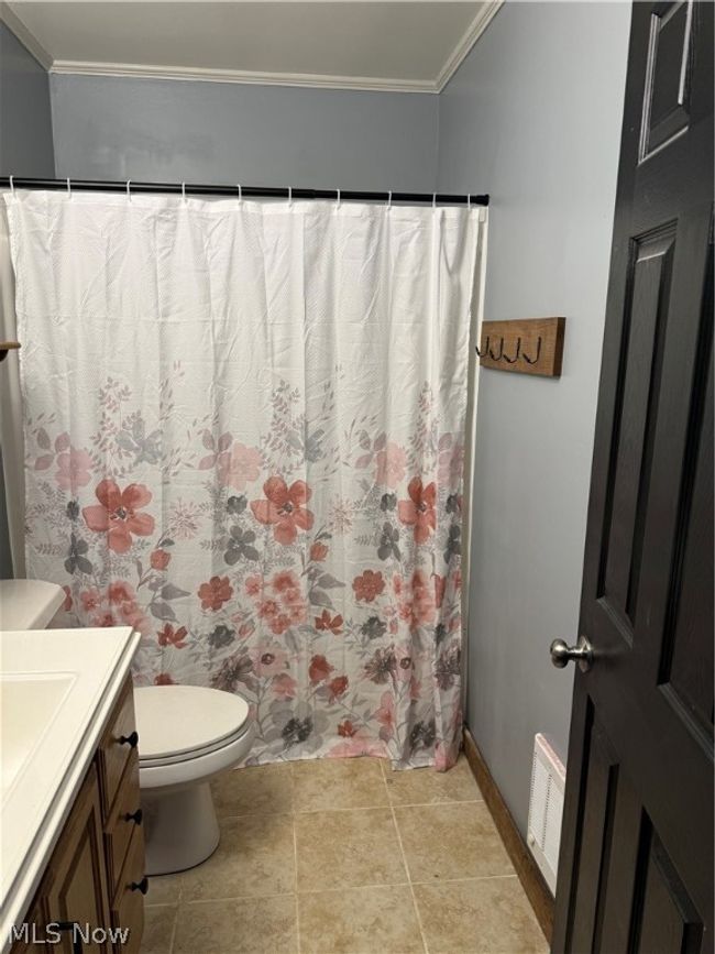 Bathroom featuring tile flooring, crown molding, toilet, and vanity | Image 9