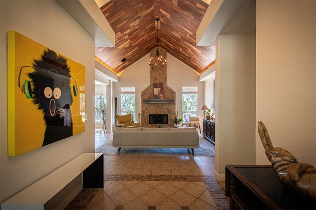 Tiled living room featuring a stone fireplace and high vaulted ceiling | Image 7