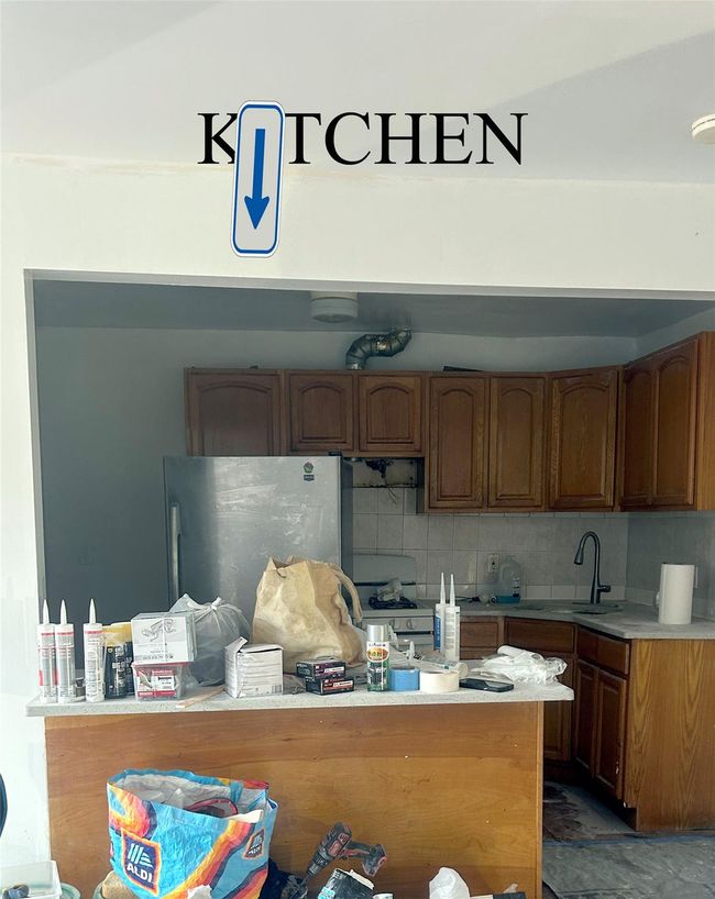 Kitchen with freestanding refrigerator, a sink, tasteful backsplash, light countertops, and brown cabinets | Image 5
