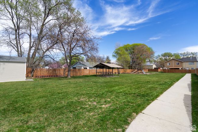 View of yard with an outbuilding, a fenced backyard, a playground, a gazebo, and a residential view | Image 23