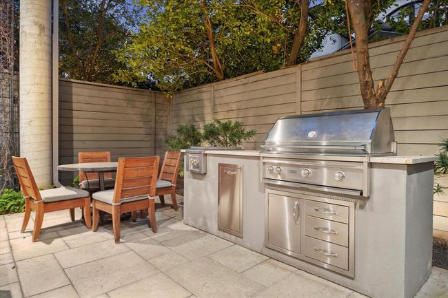 A covered outdoor KITCHEN with granite countertop prep area, stainless sink, stainless dual cooling drawers (Perlick), stainless receptacle cabinet, stainless gas grill and 2-burner Lynx cooktop. Adjacent to the Dining area and provided with a 7 foot privacy fence. | Image 41
