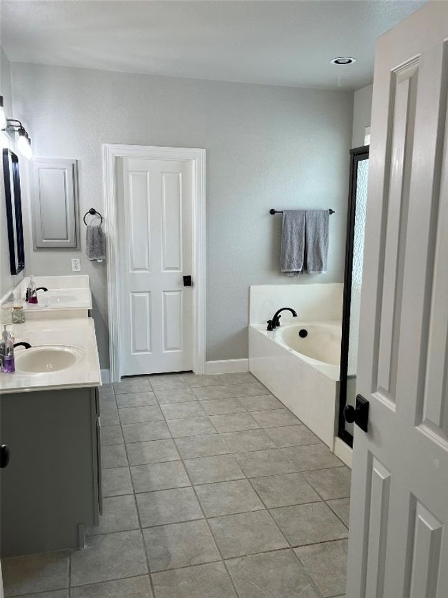 Bathroom featuring tile patterned floors, a garden tub, double vanity, and baseboards | Image 14