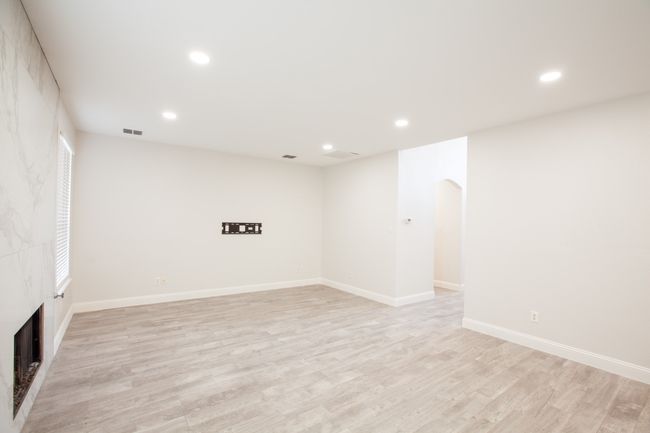Unfurnished room featuring light wood-style flooring, arched walkways, recessed lighting, and a tile fireplace | Image 16