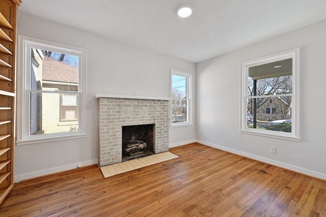 Unfurnished living room with a wealth of natural light, baseboards, a brick fireplace, and hardwood / wood-style flooring | Image 10