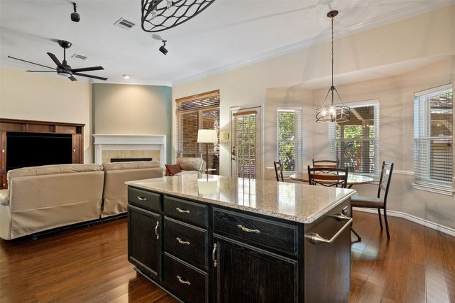 Kitchen with dark cabinetry, a fireplace, dark wood-type flooring, pendant lighting, and ceiling fan | Image 15