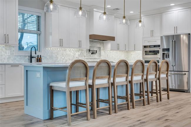 Kitchen with a kitchen breakfast bar, light countertops, decorative backsplash, visible vents, and appliances with stainless steel finishes | Image 13