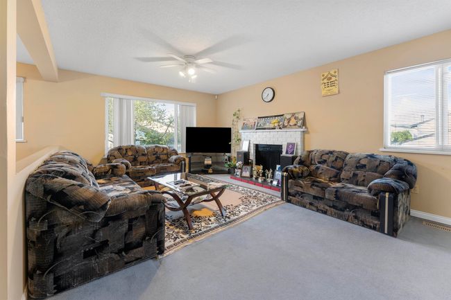 Living room featuring a ceiling fan, carpet, baseboards, visible vents, and a fireplace | Image 9