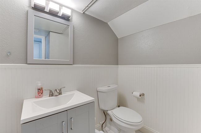 Bathroom with toilet, vanity, lofted ceiling, and a wainscoted wall | Image 22