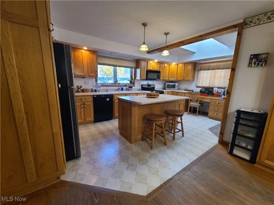 Kitchen featuring , a breakfast bar area, a skylight kitchen island, light hardwood / wood-style flooring, and custom oak cabinets | Image 3