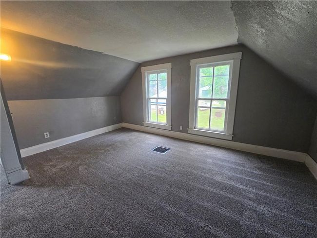 Additional living space featuring a textured ceiling, lofted ceiling, baseboards, and carpet floors | Image 11