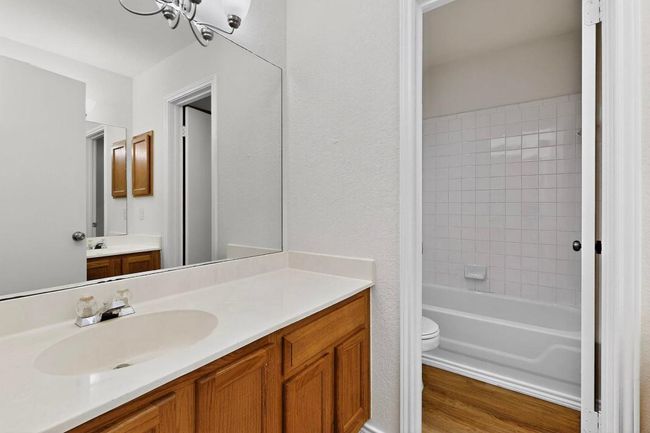 Full bathroom with toilet, vanity, wood finished floors, a chandelier, and shower combination | Image 15