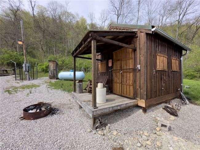 View of outbuilding with a fire pit, an outdoor structure, and a forest view | Image 7