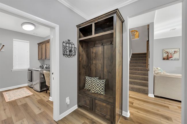 Mudroom featuring washing machine and dryer, light wood-type flooring, and ornamental molding | Image 17