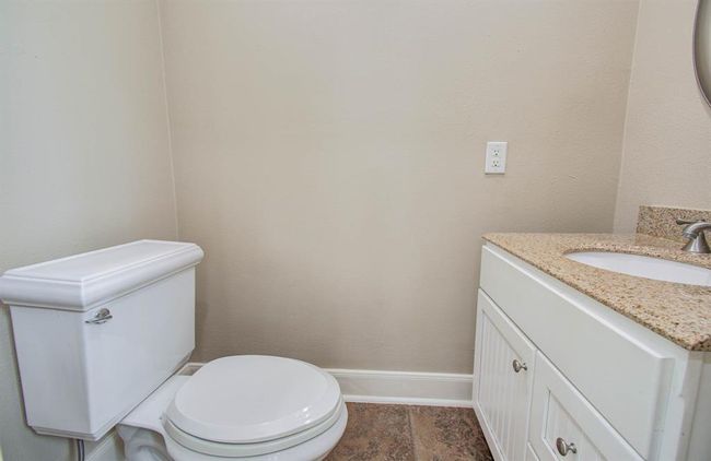 Cozy and stylish powder room featuring a sleek vanity with granite countertop and elegant fixtures. | Image 12