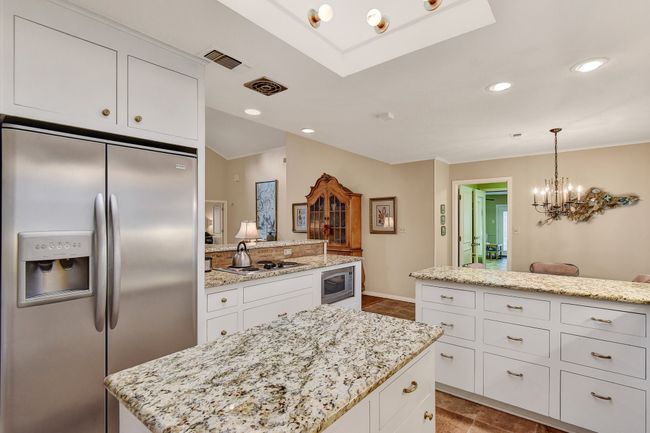 Kitchen featuring stainless steel appliances, white cabinets, a center island, a chandelier, and recessed lighting | Image 15