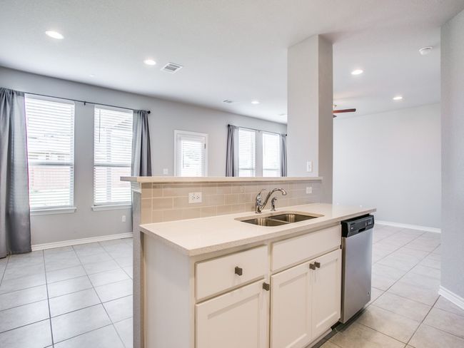 Kitchen featuring a sink, stainless steel dishwasher, decorative backsplash, light countertops, and light tile patterned floors | Image 5
