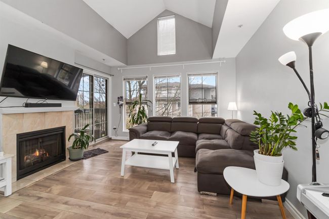 Living room with baseboards, high vaulted ceiling, wood finished floors, and a tile fireplace | Image 4