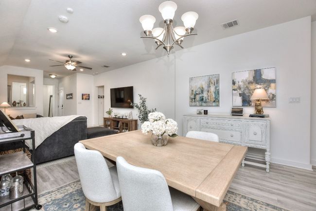 Dining area featuring light wood-type flooring, baseboards, recessed lighting, visible vents, and ceiling fan with notable chandelier | Image 12