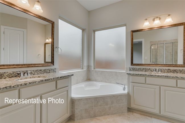 Bathroom featuring two vanities, a bath, a stall shower, and tile patterned flooring | Image 10