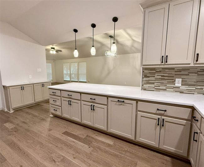 Kitchen with vaulted ceiling, a peninsula, ceiling fan, tasteful backsplash, custom cabinets and pendant lighting | Image 9
