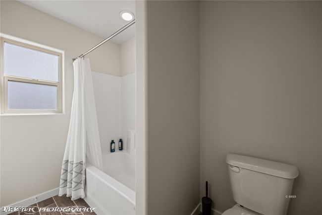 Bathroom with toilet, baseboards, shower / bath combo with shower curtain, and wood finished floors | Image 16
