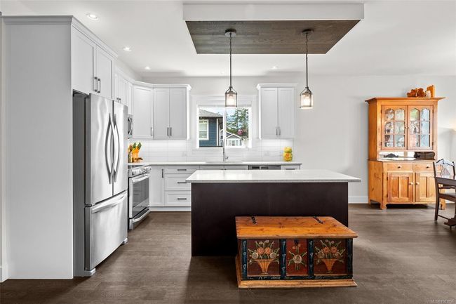 Kitchen with stainless steel appliances, light countertops, a center island, decorative backsplash, and white cabinets | Image 16