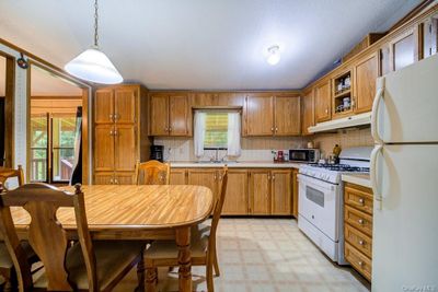 Kitchen featuring sink, white appliances, decorative backsplash, and hanging light fixtures | Image 3