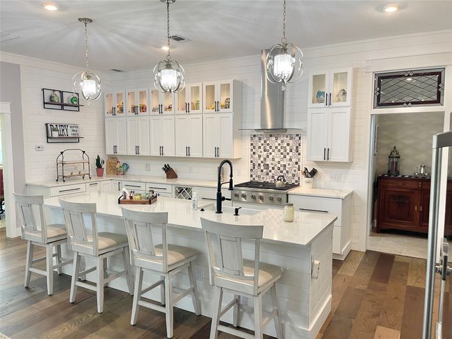 Kitchen featuring light countertops, tasteful backsplash, dark wood finished floors, a sink, and a kitchen breakfast bar | Image 11