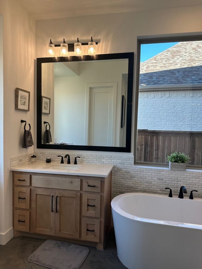 Bathroom featuring a freestanding tub, tasteful backsplash, tile patterned floors, and vanity | Image 23