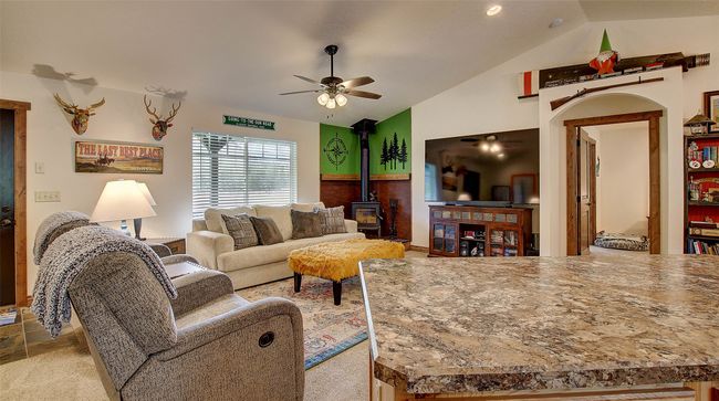 Living room featuring vaulted ceiling, a wood stove, and ceiling fan | Image 6